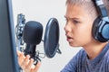 Teenager boy wearing headphones looking to computer monitor and talk using microphone set Royalty Free Stock Photo