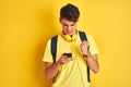 Teenager boy wearing headphones and using smartphone over isolated background annoyed and frustrated shouting with anger, crazy