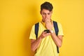 Teenager boy wearing headphones and using smartphone over isolated background cover mouth with hand shocked with shame for Royalty Free Stock Photo