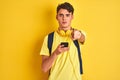 Teenager boy wearing headphones and using smartphone over isolated background pointing with finger to the camera and to you, hand Royalty Free Stock Photo