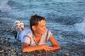 Teenager boy in wet clothes lying on seacoast