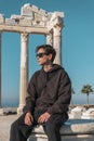 A teenager in a brown suit sits thoughtfully against the ruins of the Temple of Apollo in Side Turkey Royalty Free Stock Photo