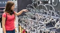 Teenager brunette girl in coral t-shirt with long hair choosing a bathroom or kitchen water tap in a home furnishings retail store Royalty Free Stock Photo