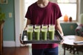 teenager carrying a tray of spinach and berry smoothies