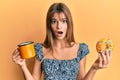 Teenager caucasian girl eating doughnut and drinking coffee afraid and shocked with surprise and amazed expression, fear and Royalty Free Stock Photo