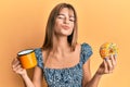 Teenager caucasian girl eating doughnut and drinking coffee looking at the camera blowing a kiss being lovely and sexy Royalty Free Stock Photo