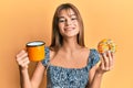 Teenager caucasian girl eating doughnut and drinking coffee smiling with a happy and cool smile on face Royalty Free Stock Photo