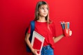 Teenager caucasian girl holding art notebooks and colored pencils smiling looking to the side and staring away thinking Royalty Free Stock Photo