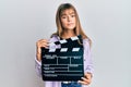 Teenager caucasian girl holding video film clapboard relaxed with serious expression on face