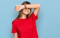 Teenager caucasian girl wearing casual red t shirt covering eyes with arm smiling cheerful and funny