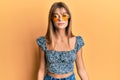 Teenager caucasian girl wearing fashion yellow sunglasses with serious expression on face Royalty Free Stock Photo