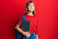 Teenager caucasian girl wearing student backpack and holding computer laptop looking positive and happy standing and smiling with Royalty Free Stock Photo