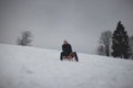 Teenager caught riding on a wooden sledge trying to adjust his direction with his hand and concentrating on his ride. In winter,