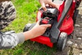 Teenager changes rechargeable battery in electric lawn mower Royalty Free Stock Photo