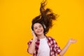 Teenager child girl in headphones listening music, wearing stylish casual outfit isolated over yellow background. Happy Royalty Free Stock Photo