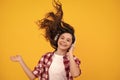 Teenager child girl in headphones listening music, wearing stylish casual outfit  over yellow background. Happy Royalty Free Stock Photo
