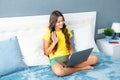 Teenager child girl lying in a bed of laptop, communicating with friends on the laptop. Teen girl doing homework on