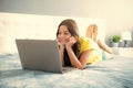 Teenager child girl working on laptop pc computer lying in bed resting relaxing in bedroom at home. teen girl, positive Royalty Free Stock Photo