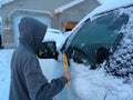 Teenager cleaning snow off a vehicle