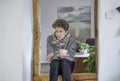 A teenager with a cold sits on a beam in his house and holds a cup in his hand Royalty Free Stock Photo