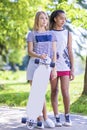 Teenager Concepts. Two Teenage Girlfriends Together With Longboard Outdoors in Park.