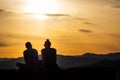 Teenager couple with sunglasses sitting on hill enjoying the sunset