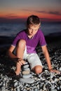 Teenager creates pyramid from pebble on seacoast Royalty Free Stock Photo