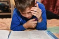 Teenager cries while solving a difficult school homework in a room on a bed Royalty Free Stock Photo