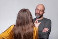 Teenager daughter and father interaction. Girl with long hair back to camera in focus, Expressive hand gesture Father bald with Royalty Free Stock Photo