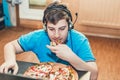 Teenager eating pizza sitting at a laptop. Royalty Free Stock Photo