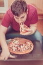 Teenager eating pizza sitting at a laptop. Royalty Free Stock Photo