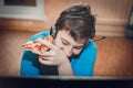 Teenager eating pizza sitting at a laptop. Royalty Free Stock Photo