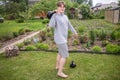 A teenager is engaged in weightlifting with heavy weights in a flowering summer garden