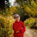 A teenager in a fall park pondered. A boy in a red suit in a park in the fall