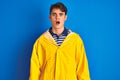 Teenager fisherman boy wearing yellow raincoat over isolated background afraid and shocked with surprise expression, fear and