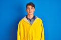 Teenager fisherman boy wearing yellow raincoat over isolated background with a happy and cool smile on face