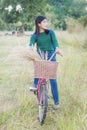 Teenager girl, bicycle with flowers basket in outdoor landscape