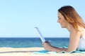 Teenager girl browsing social media in a tablet on the beach