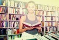 Teenager girl brunete looks for the right book in library Royalty Free Stock Photo