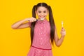 Teenager girl brushing her teeth over isolated yellow background. Daily hygiene teen child hold toothbrush, morning Royalty Free Stock Photo