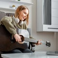 Teenager girl closeup portrait learning play guitar at home using online lessons. Hobby remote musical education