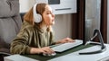 Teenager girl cybersportman gamer play online computer game at home alone in leisure time. Young blonde woman in headphones Royalty Free Stock Photo