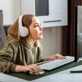 Teenager girl cybersportman gamer play online computer game at home alone in leisure time. Young blonde woman in Royalty Free Stock Photo