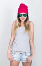 Teenager girl in denim shorts and a gray T-shirt and a pink knit hat, tied at the hips plaid shirt. girl in sunglasses Royalty Free Stock Photo