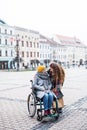 A teenager girl with disabled grandmother in wheelchair outdoors on the street in winter. Royalty Free Stock Photo