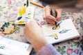 Teenager girl drawing bird in small paper drawing-pad. Close-up kid artist painting small picture on paper notepad with Royalty Free Stock Photo