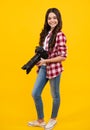 Teenager girl with dslr photo camera with zoom lens. Child photographer isoalted on yellow background. Photo school Royalty Free Stock Photo