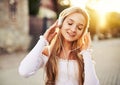 Teenager girl enjoying life and walking on a street, while listening to music with headphones on her head with the sunset in the Royalty Free Stock Photo