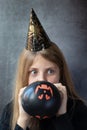 A teenager girl in a Halloween paper cap inflating black ball for Halloween. People, Halloween, decoration concept
