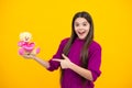Teenager girl hold soft toy for birthday on yellow background. Teen with toy teddy bear with love heart for valentines Royalty Free Stock Photo